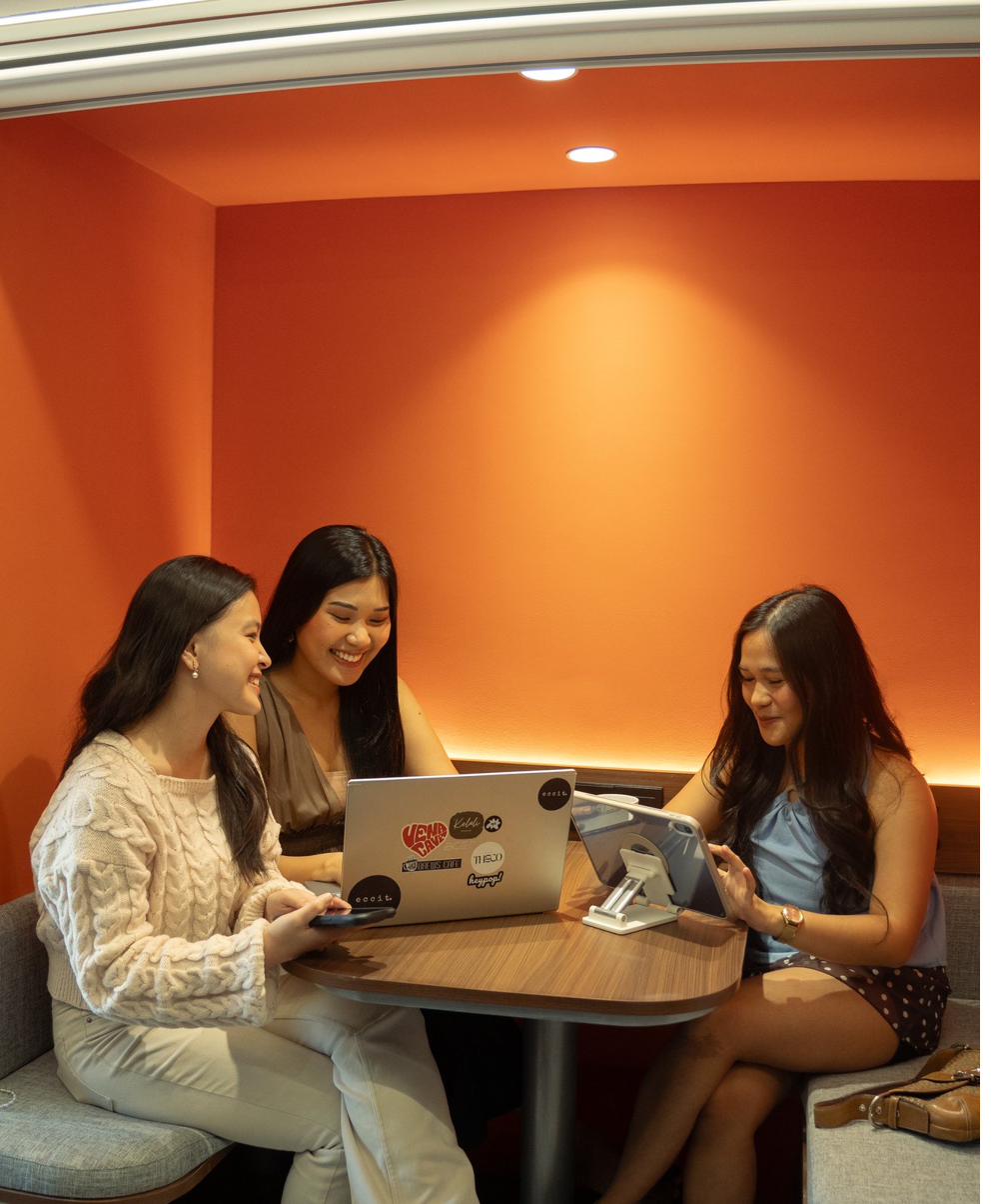Co/Lab — three people collaborating in the orange booth